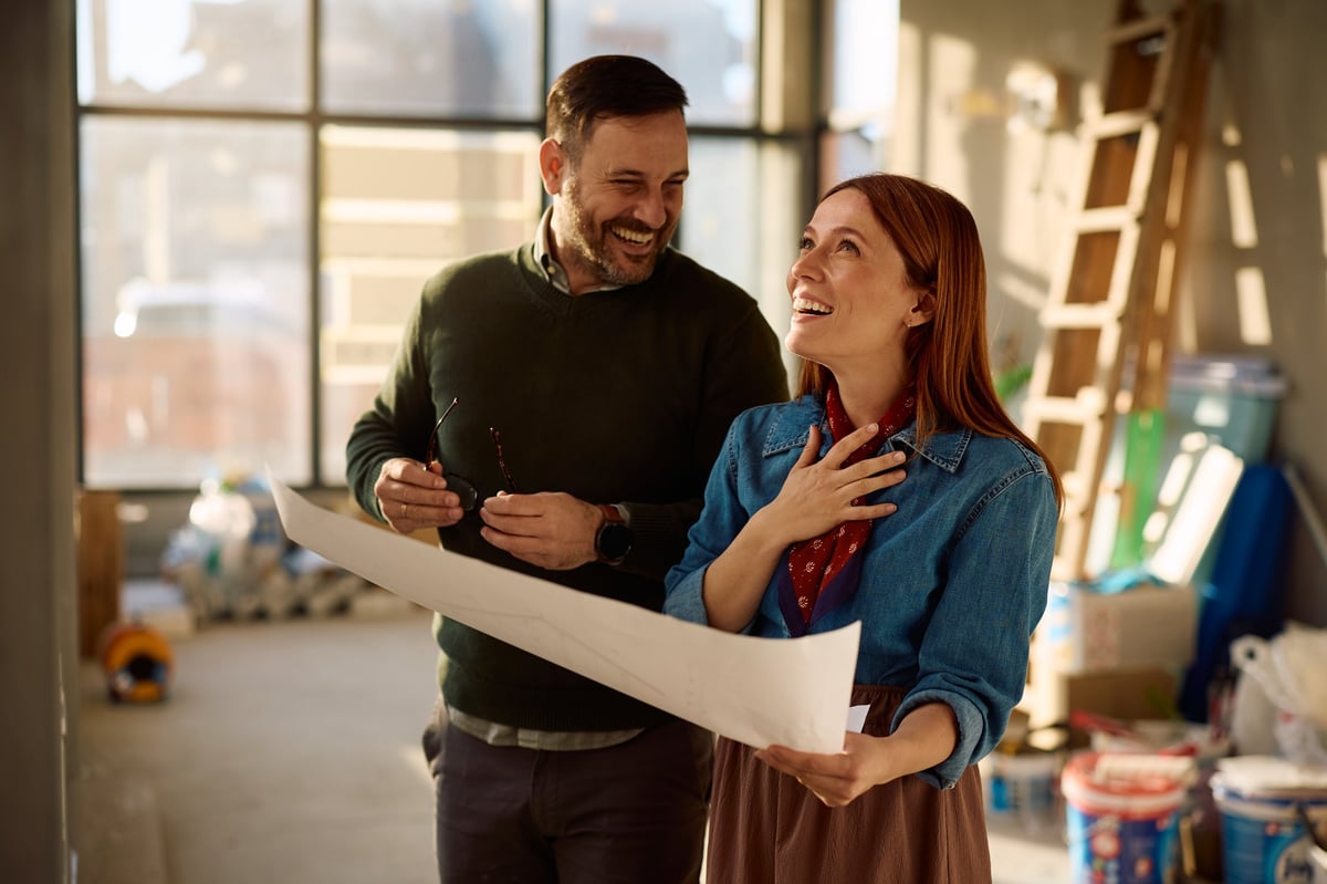 Homeowners smiling with blueprints during a home remodeling project