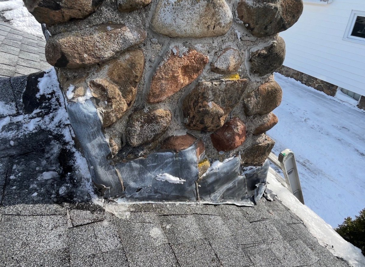 Close-up of concrete chimney base with rusted metal banding and deteriorating mortar, viewed from above